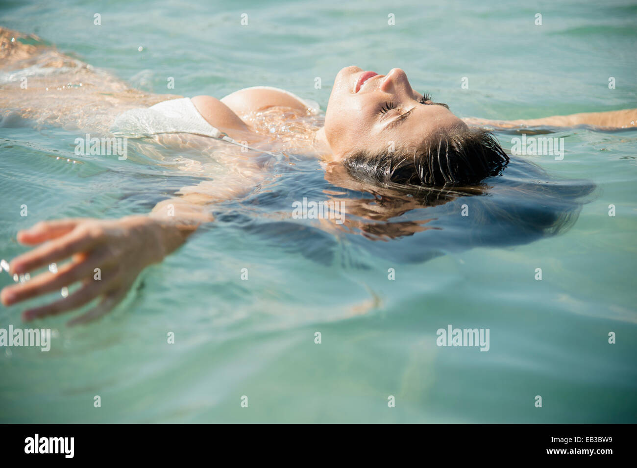 Caucasian woman floating in ocean Stock Photo