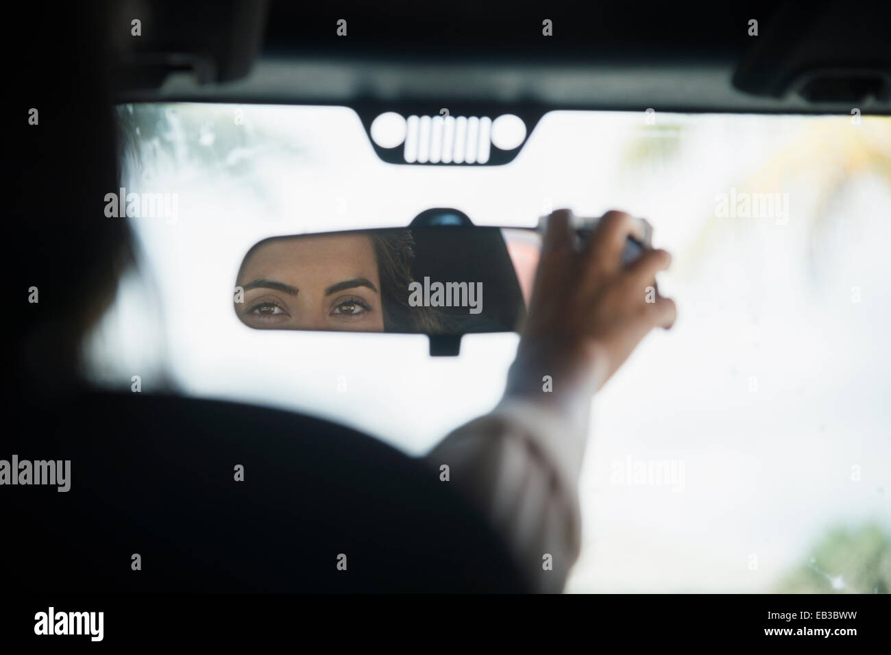 Caucasian woman adjusting rear view mirror in car Stock Photo