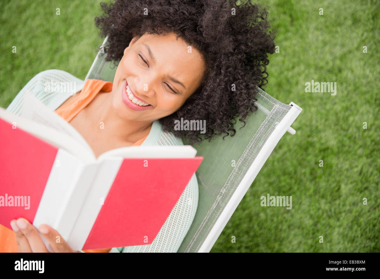High angle view of woman reading book in chair outdoors Stock Photo