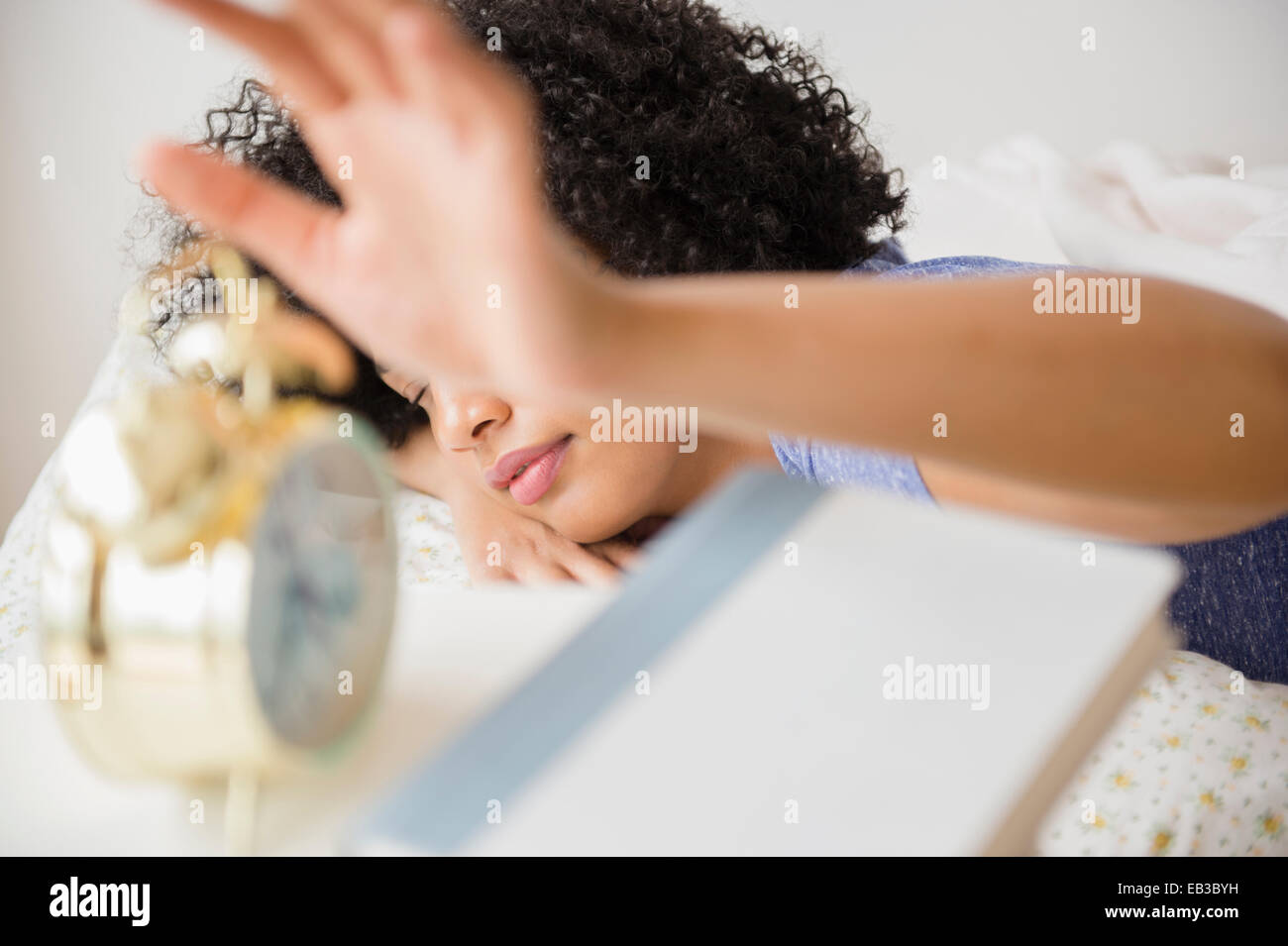 Woman turning off alarm clock in bedroom Stock Photo