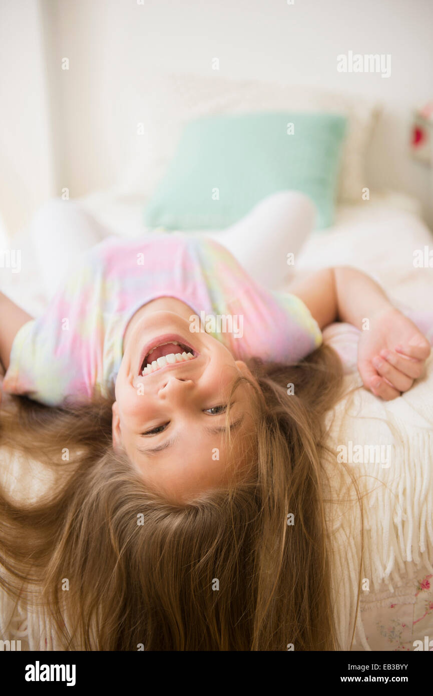Caucasian girl playing on bed Stock Photo