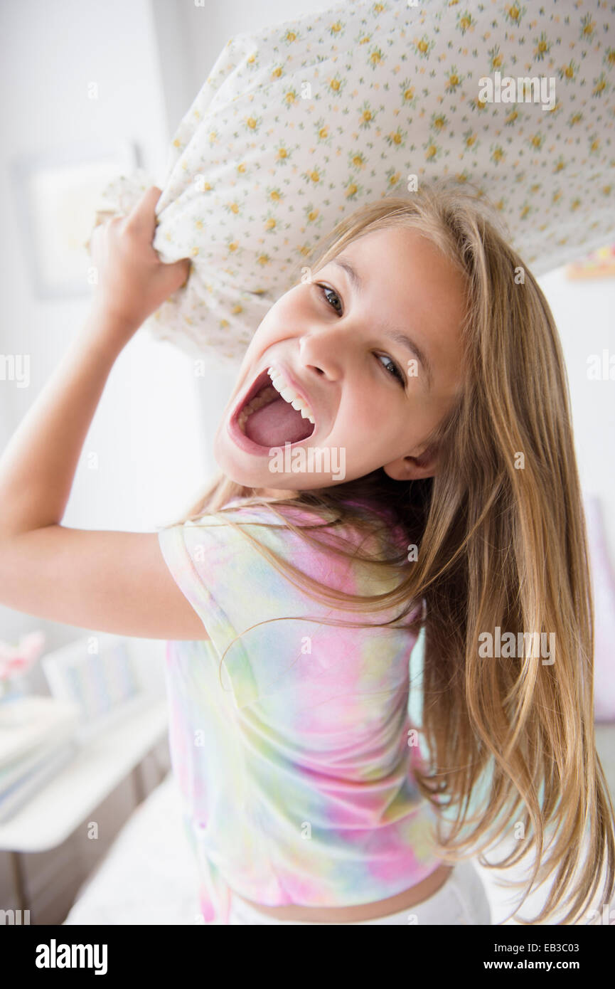 Caucasian girl having pillow fight in bedroom Stock Photo