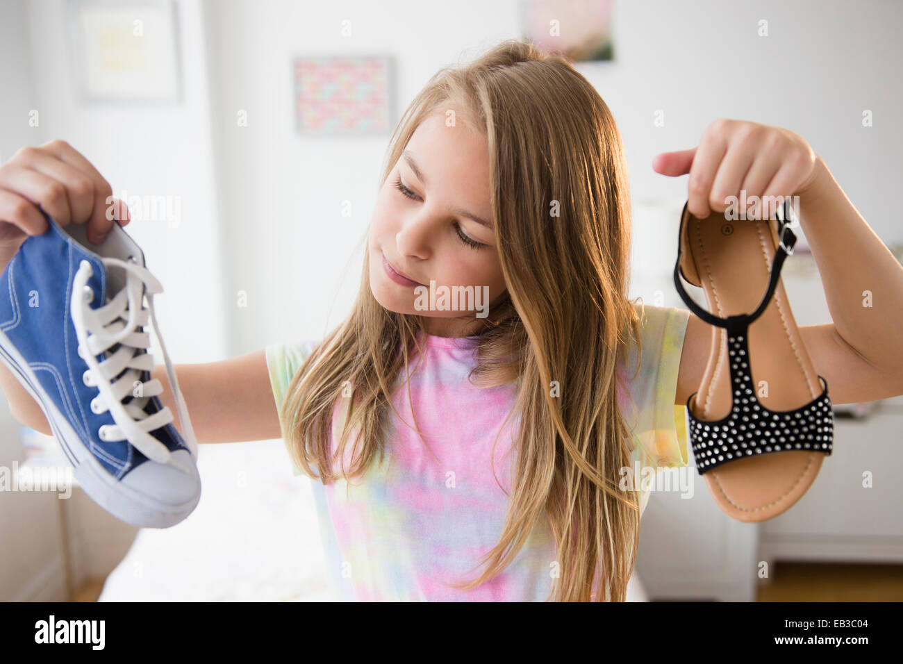Caucasian girl picking shoes in bedroom Stock Photo