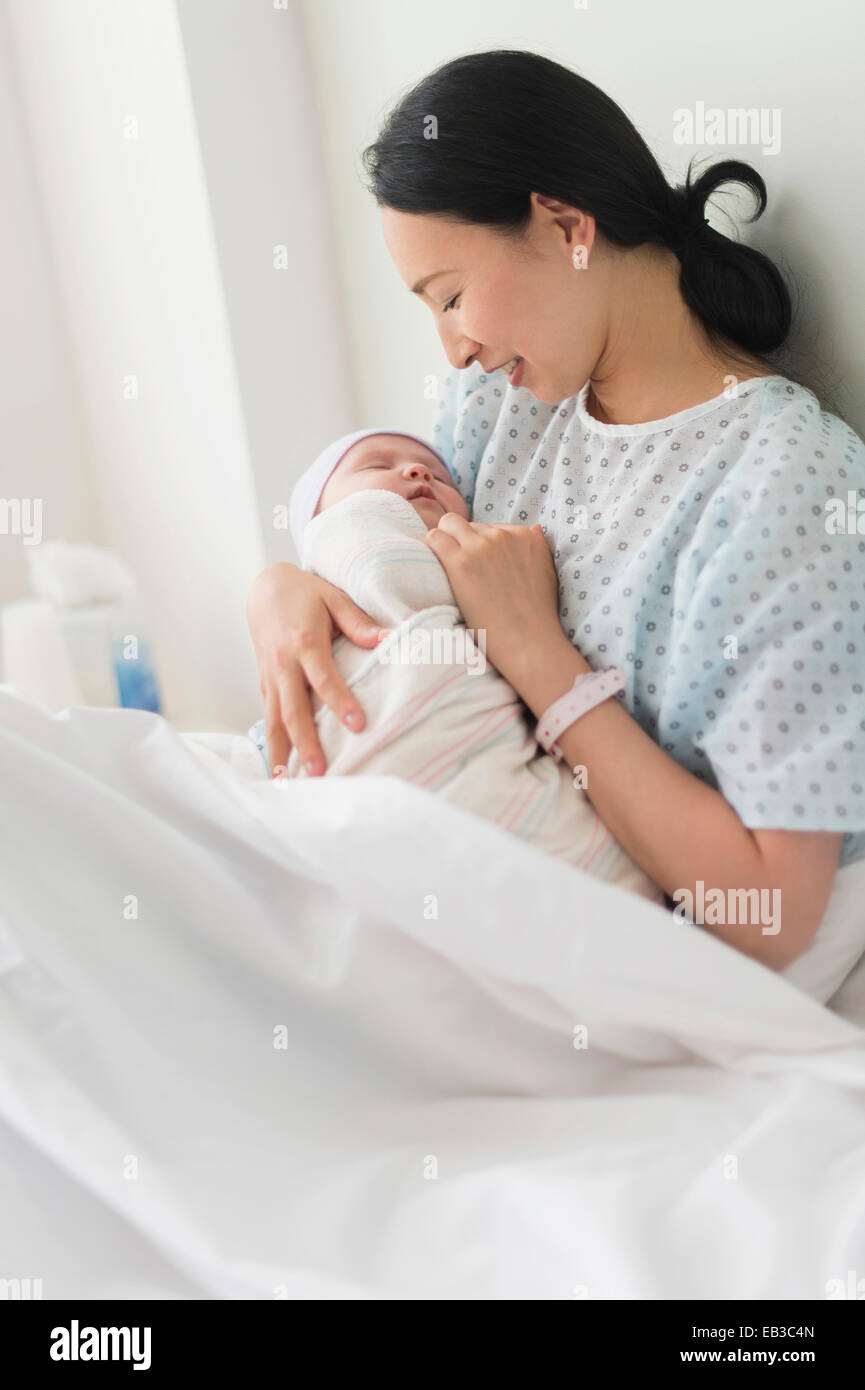 Asian mother holding newborn baby in hospital bed Stock Photo