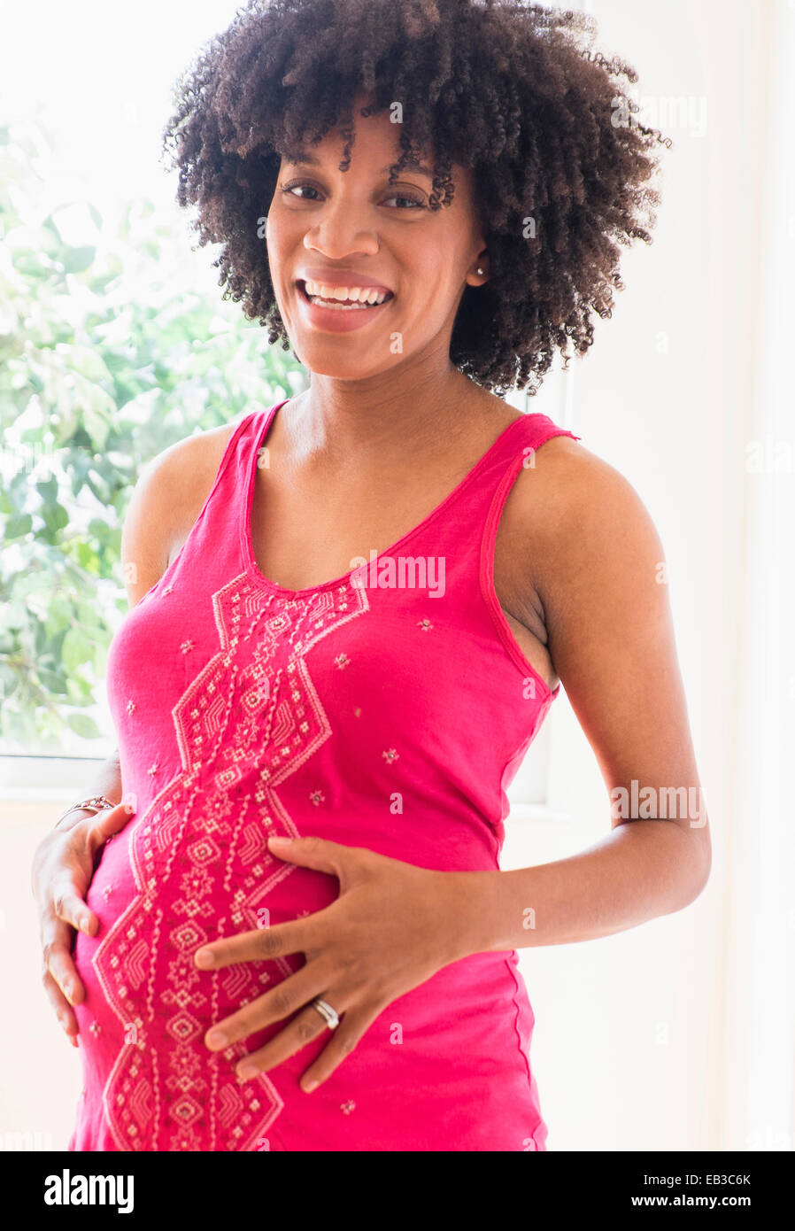Pregnant African American mother holding her stomach Stock Photo - Alamy