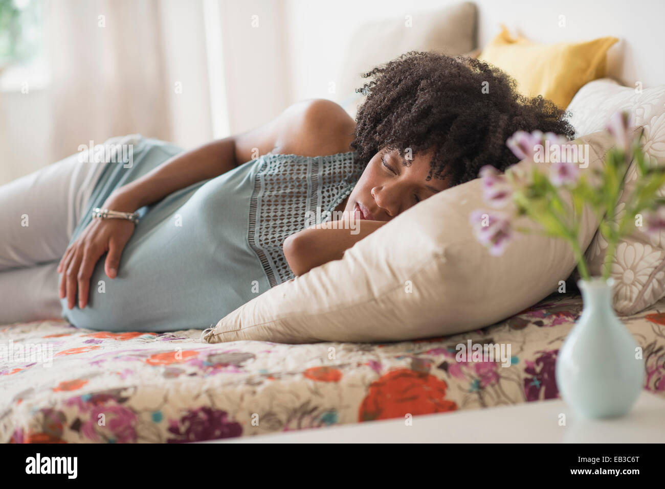 Pregnant African American mother holding her stomach in bed Stock Photo