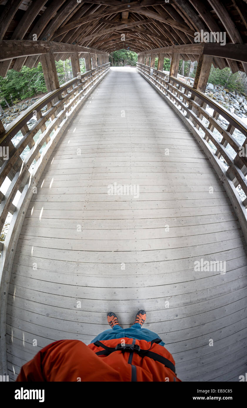 Man standing on a wooden bridge taking a photo, Whistler, British Columbia, Canada Stock Photo