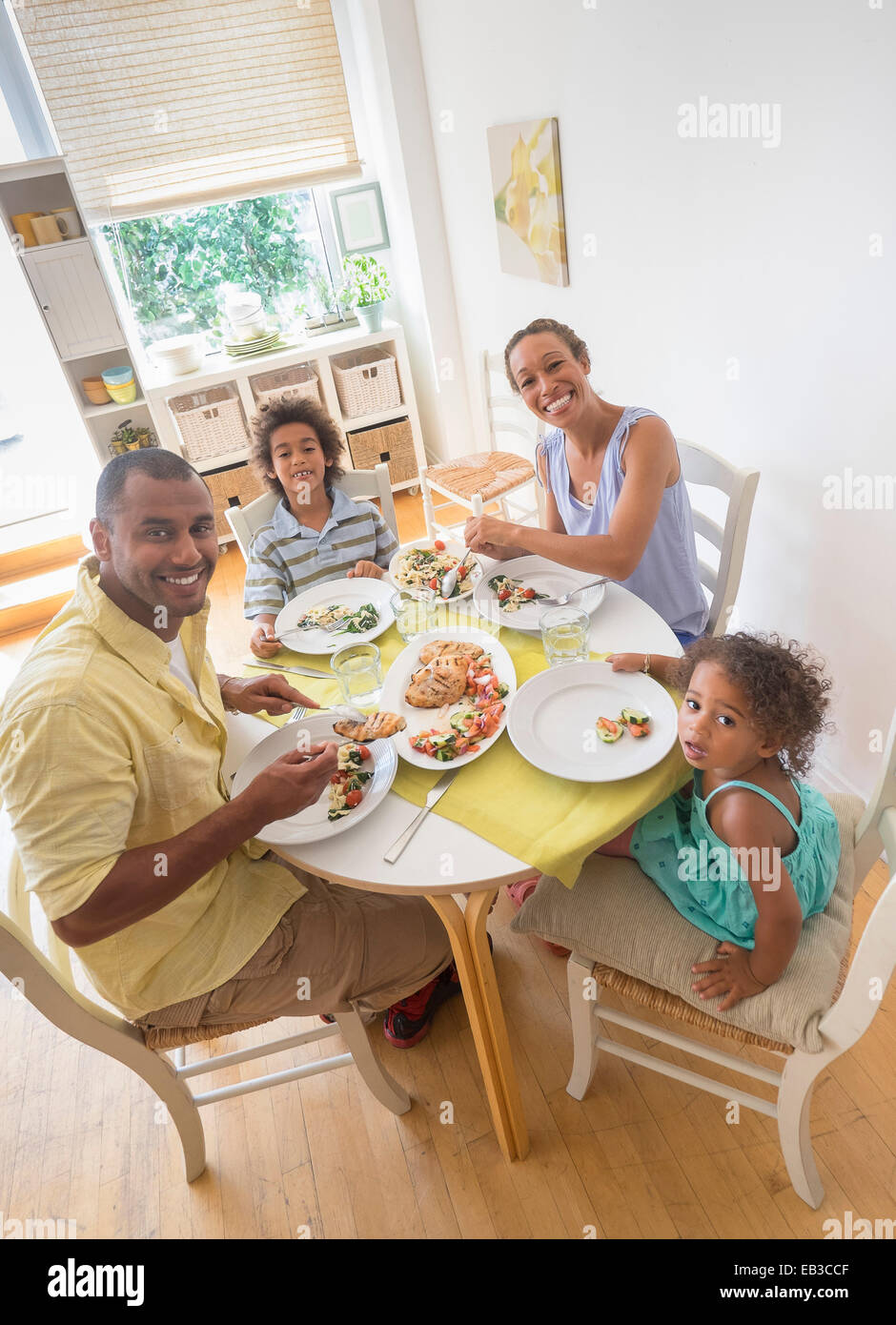 Mixed race family smiling at dining room table Stock Photo - Alamy