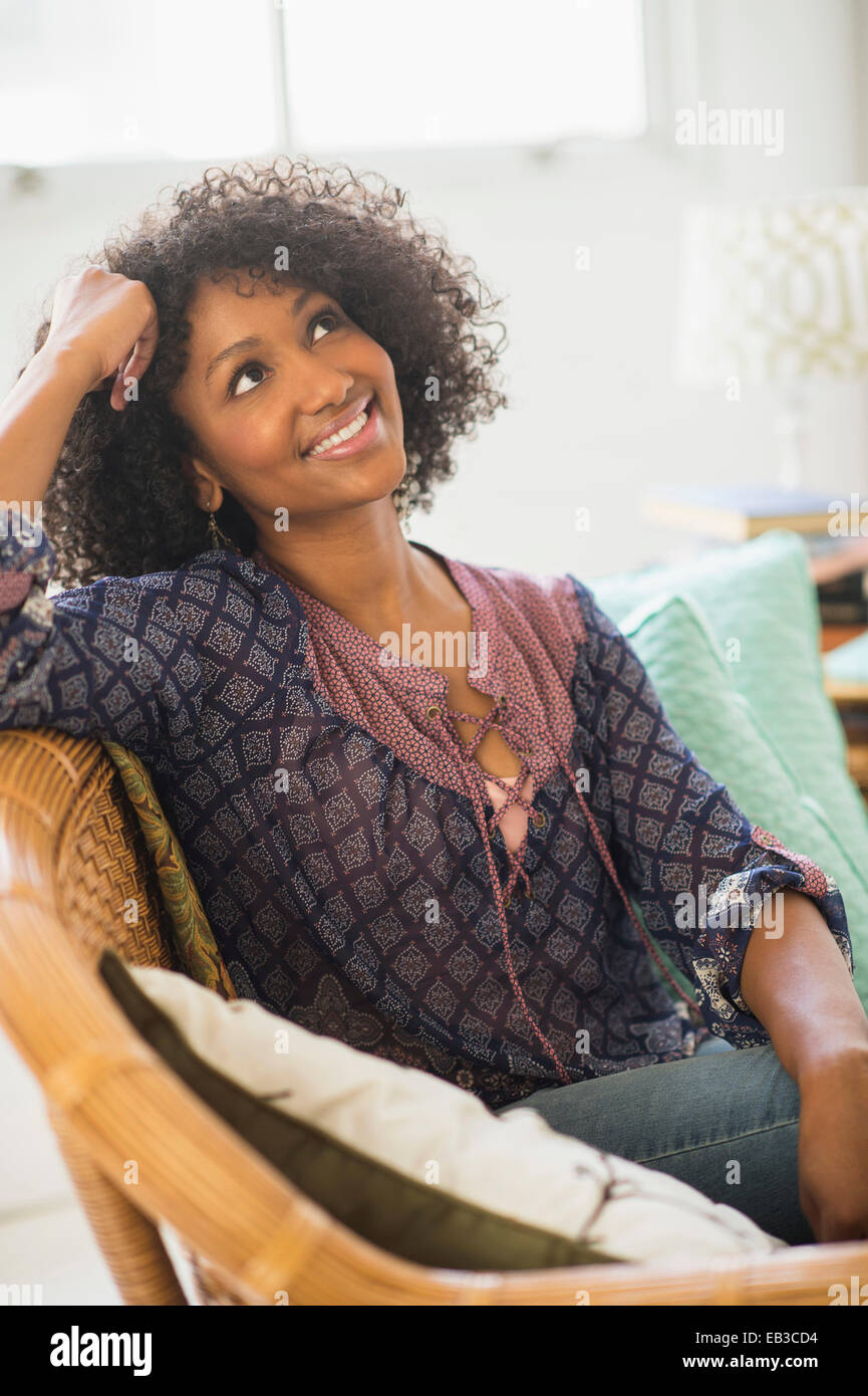 Mixed race woman smiling in living room Stock Photo