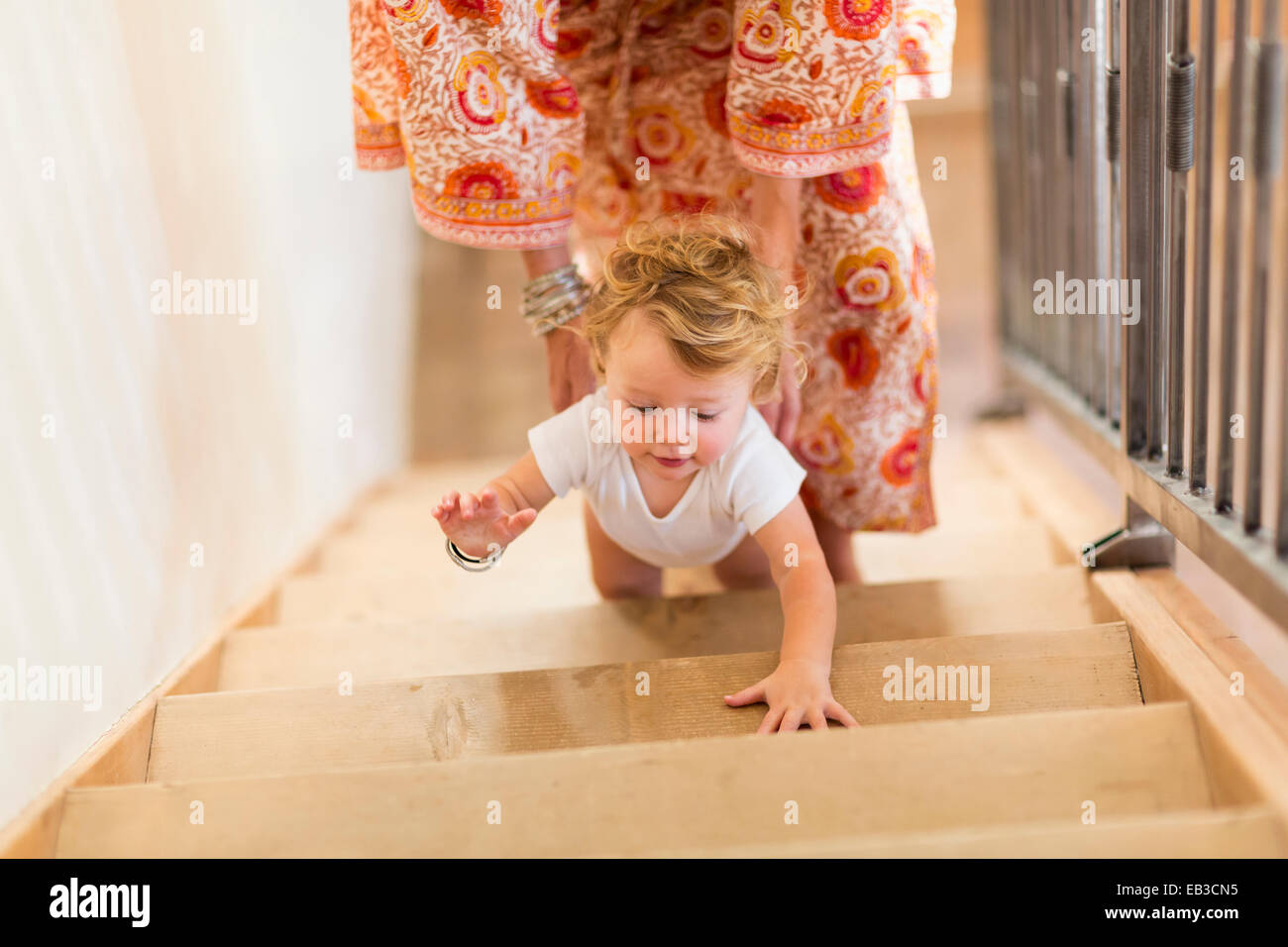 Caucasian mother helping baby son climb stairs Stock Photo Alamy
