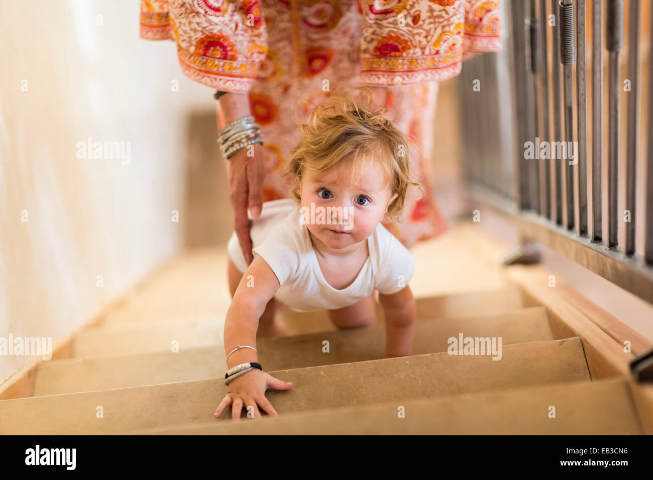 Caucasian mother helping baby son climb stairs Stock Photo Alamy