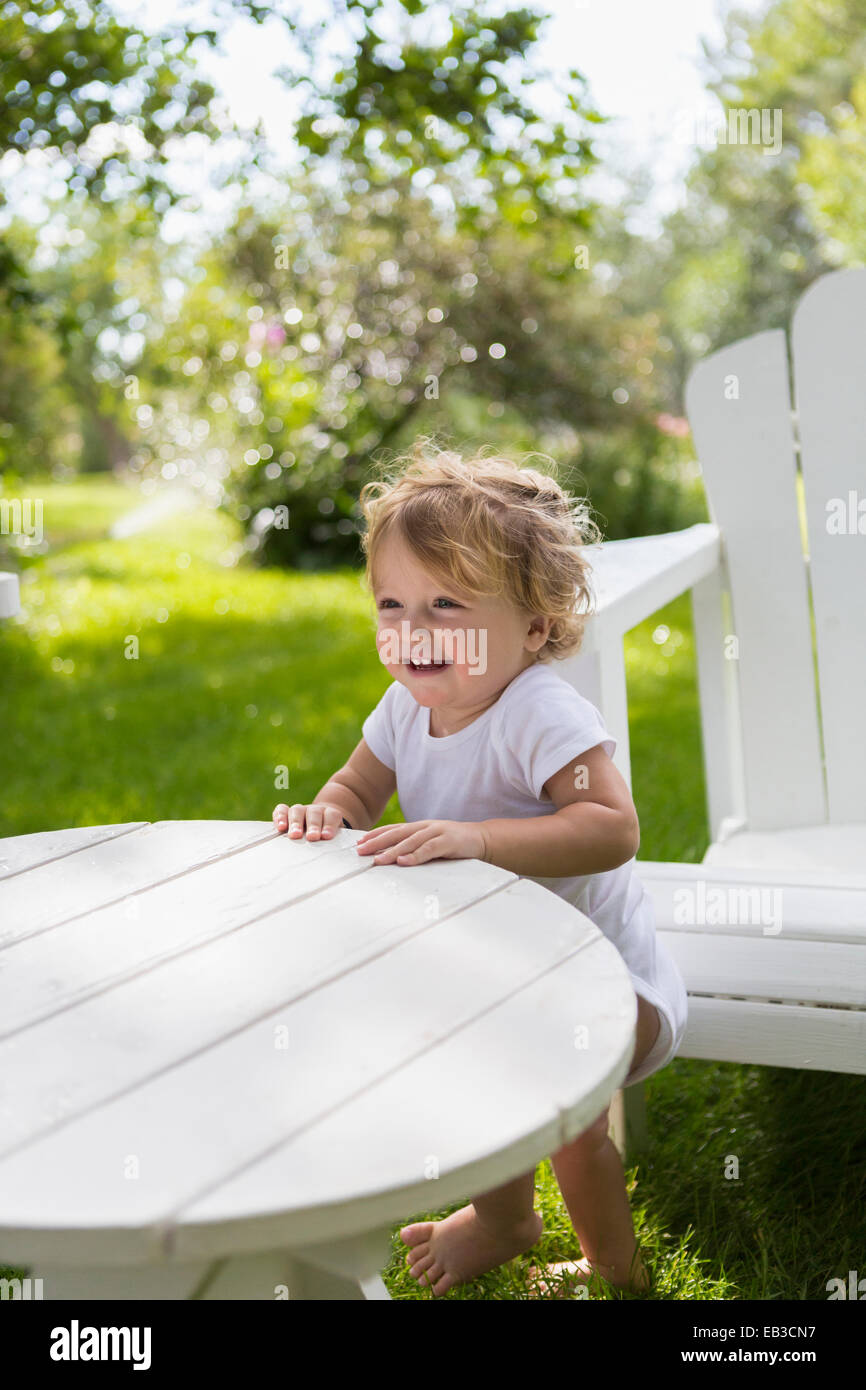 Caucasian baby boy standing at table in backyard Stock Photo