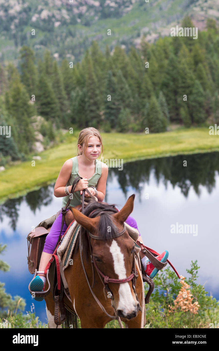 Caucasian girl riding horse in near lake Stock Photo