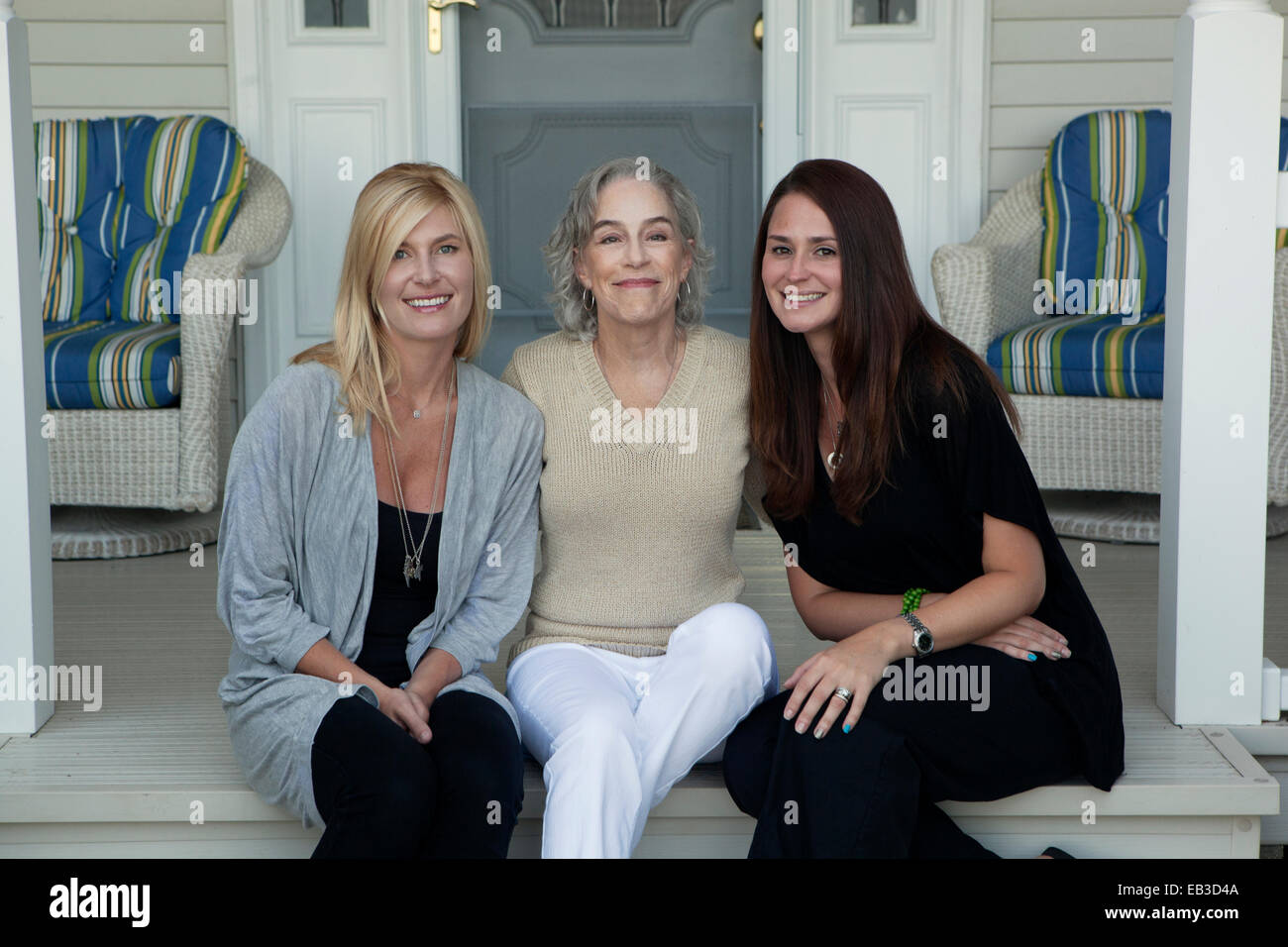 Caucasian mother and daughters smiling on front porch Stock Photo