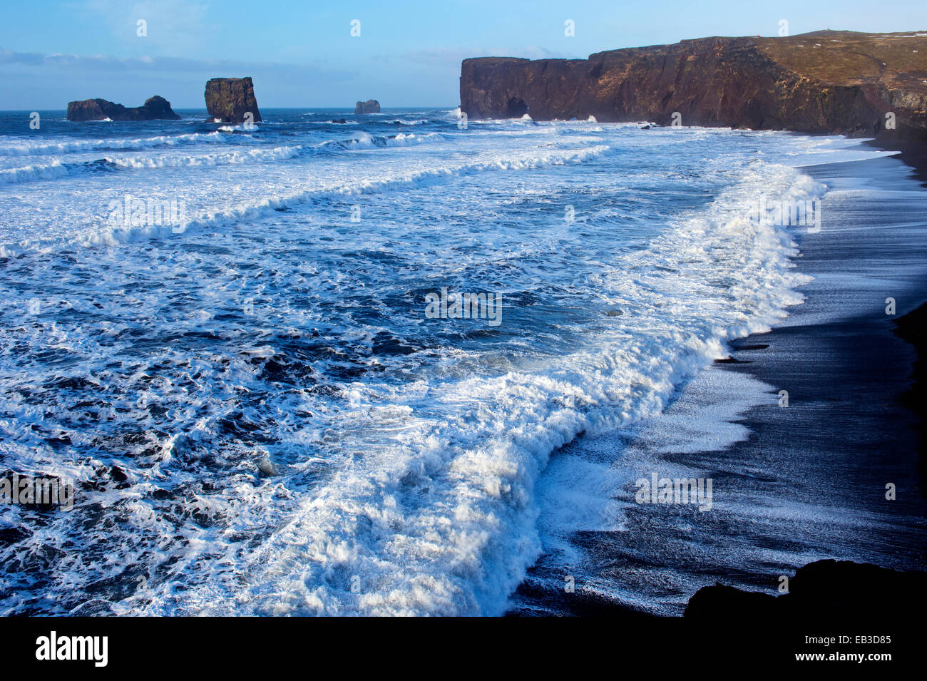 Waves washing up by rocky cliffs on beach Stock Photo