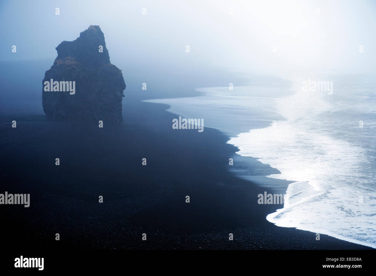 Waves washing up by rock formation on beach Stock Photo