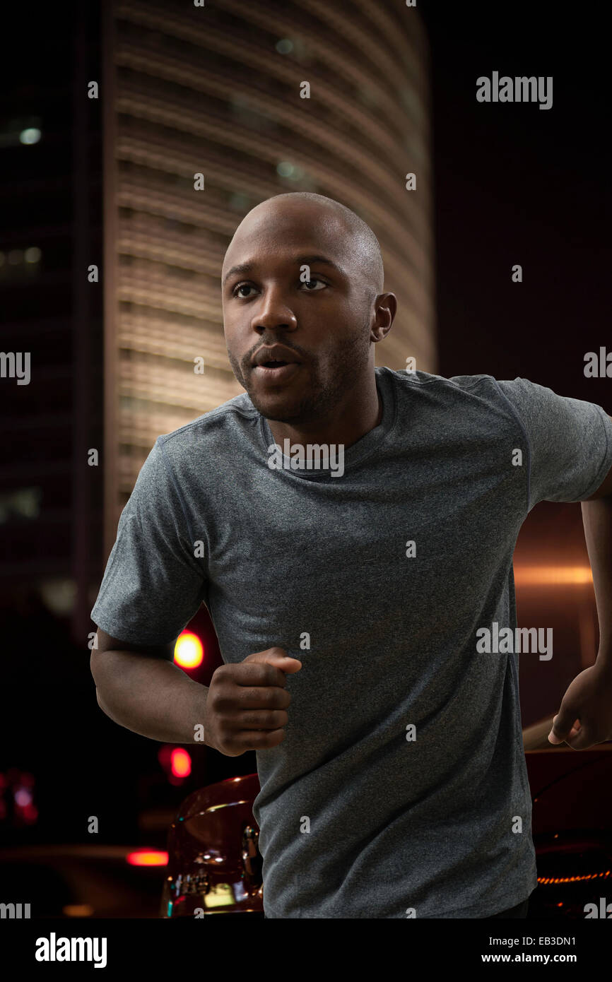 Black man running in city at night Stock Photo