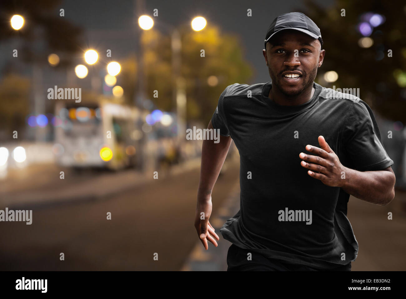 Black man running on city street at night Stock Photo