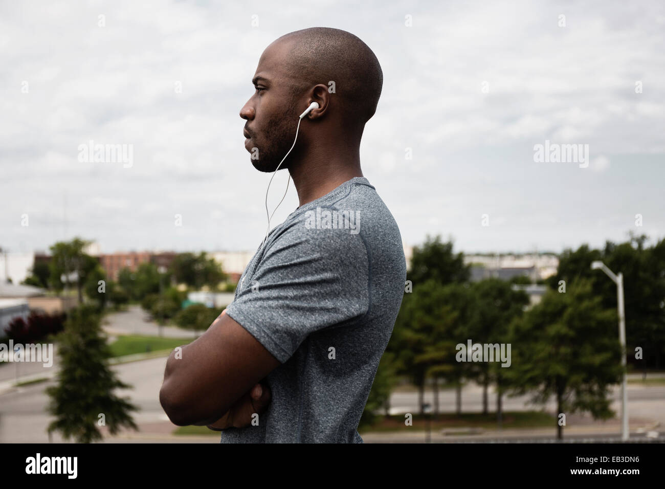 Black runner listening to earbuds in urban park Stock Photo