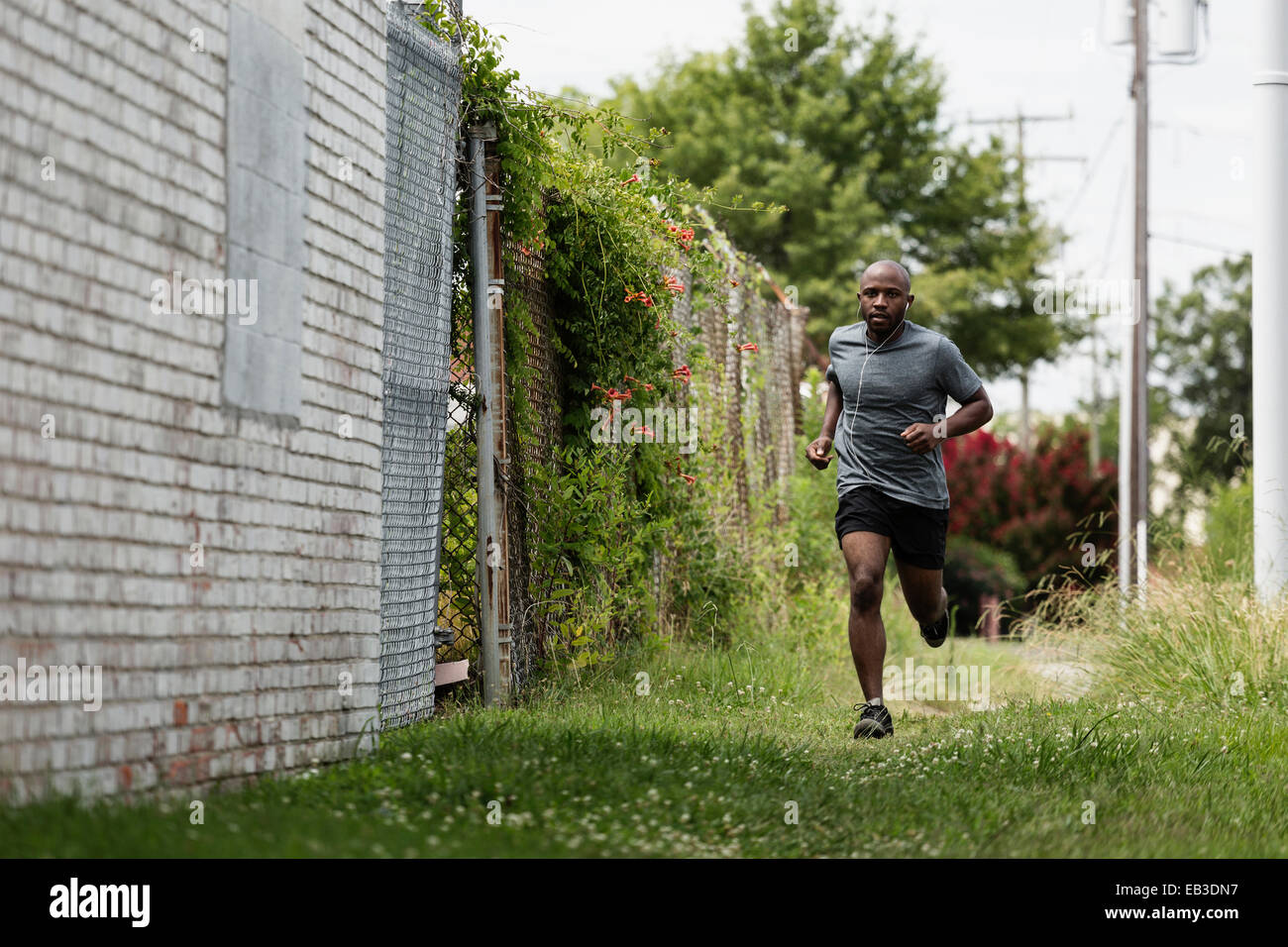 Black man running in urban grass Stock Photo