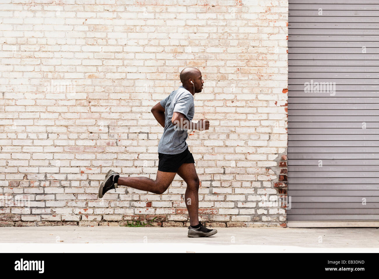 Black man running on city sidewalk Stock Photo