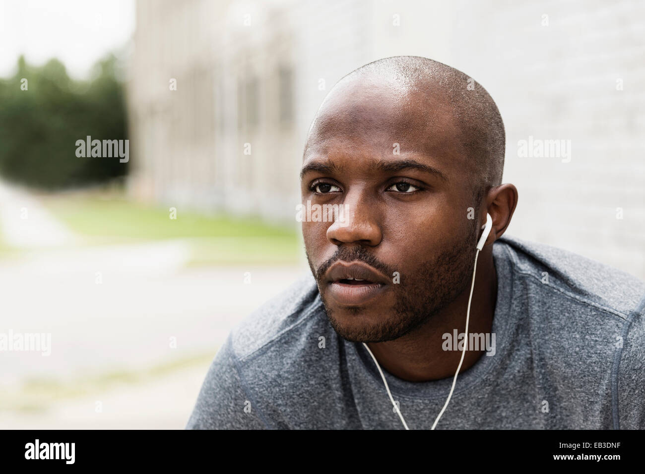 Black runner resting in city with earbuds Stock Photo