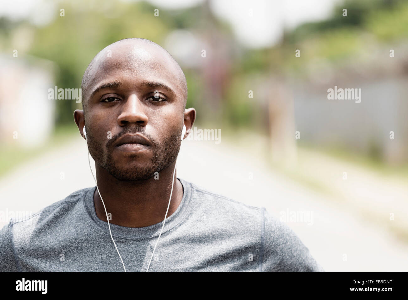 Black runner resting on city street with earbuds Stock Photo