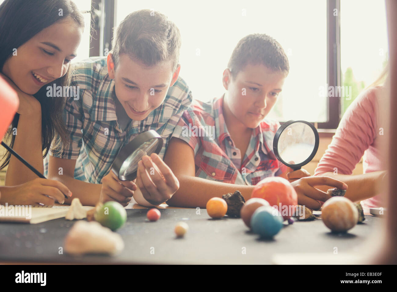 Students examining models of planets in classroom Stock Photo