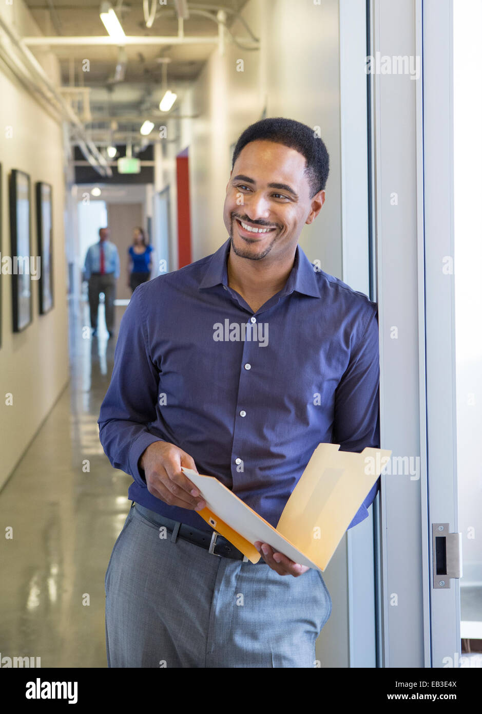 Black businessman holding folder in office hallway Stock Photo