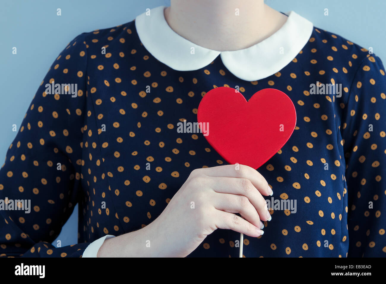 Woman wearing polka dot dress holding heart shape object Stock Photo