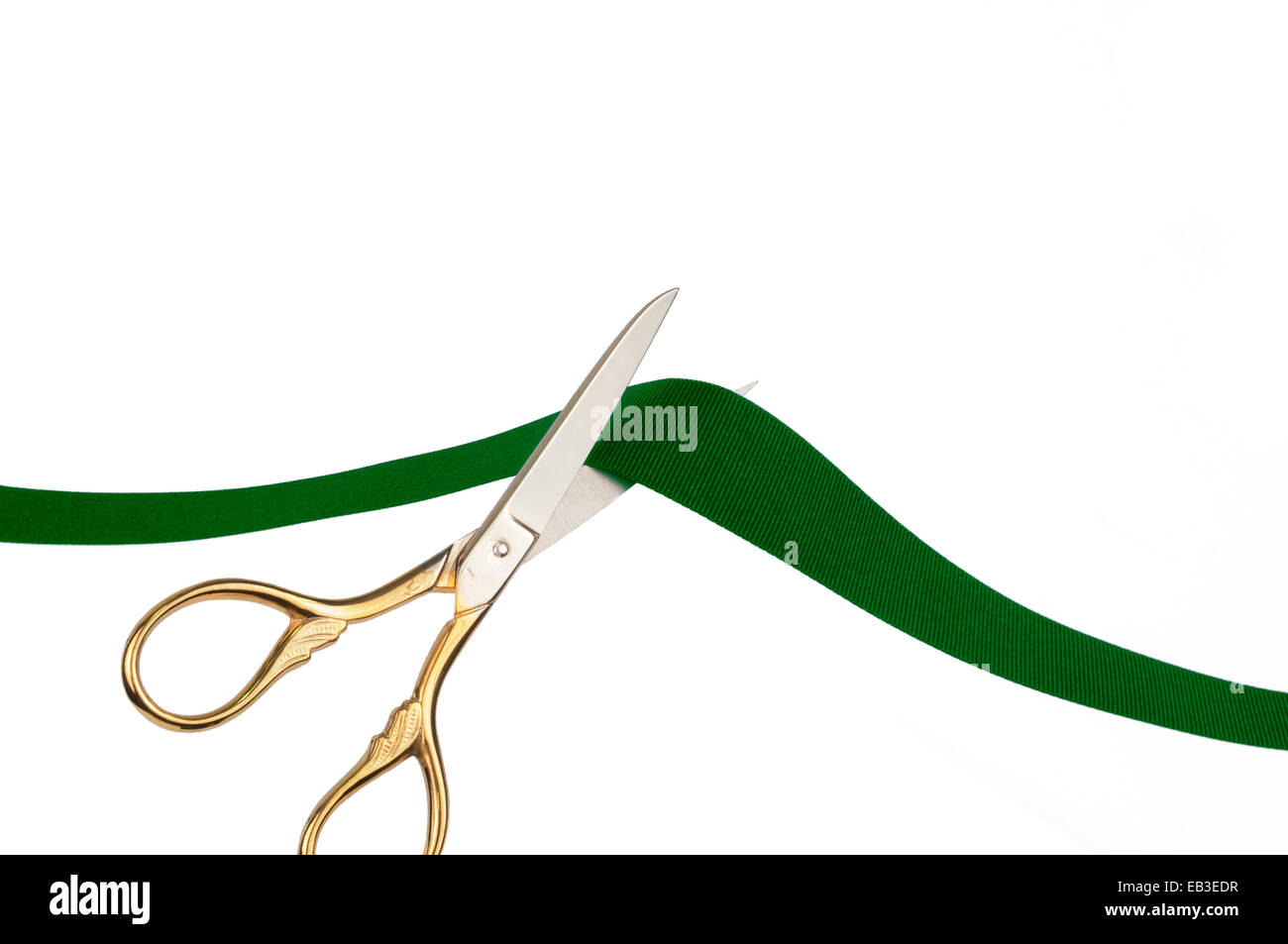 Scissors cutting a green ribbon Stock Photo