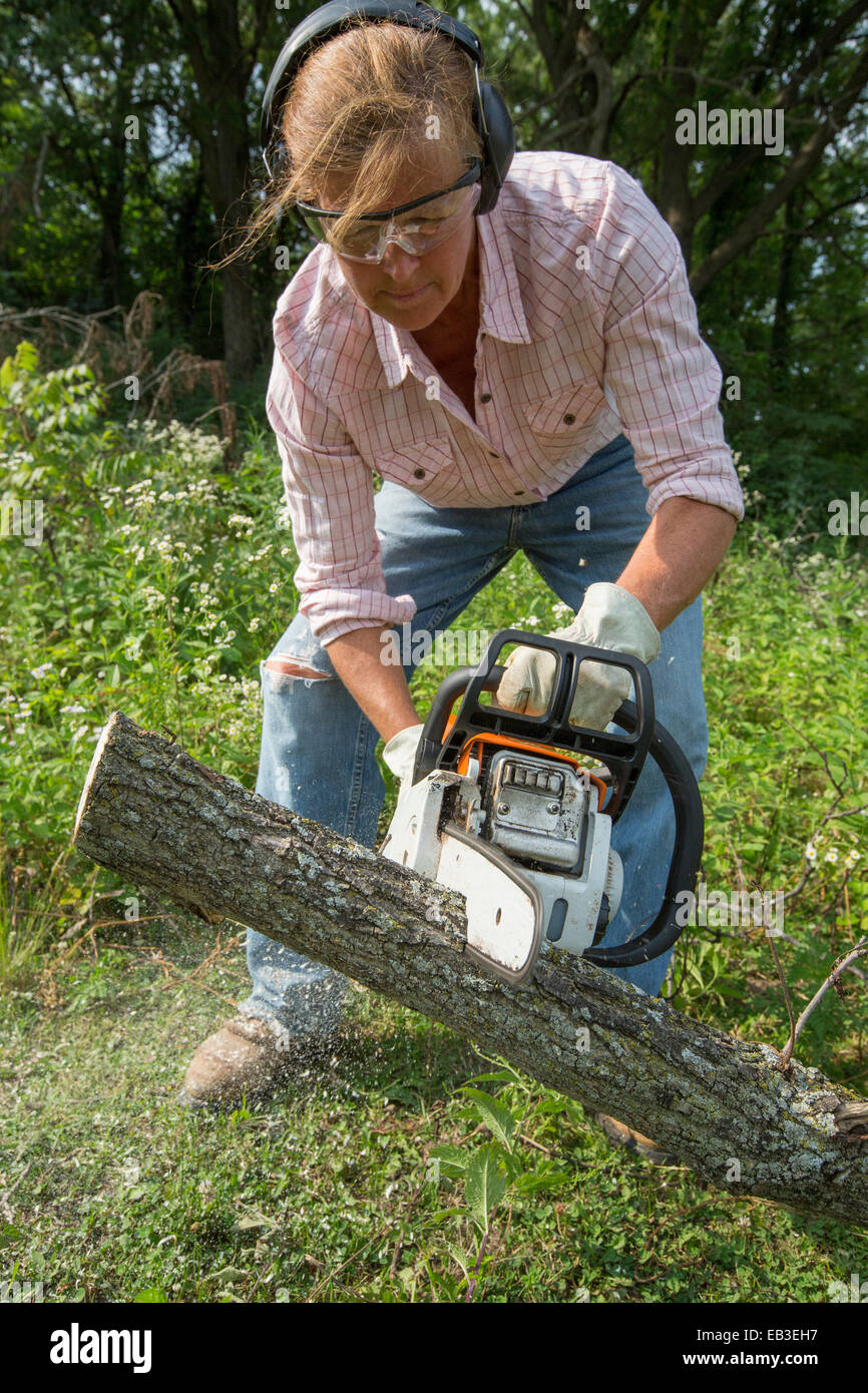 Caucasian woman using chain saw to cut wood Stock Photo Alamy