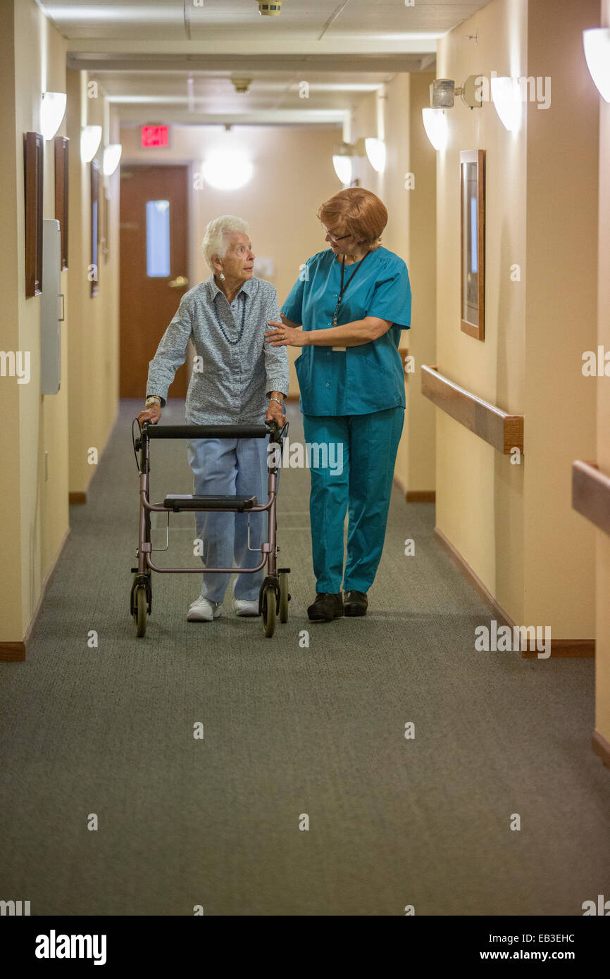 Older Caucasian woman walking with nurse in nursing home Stock Photo