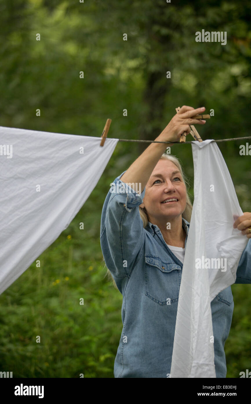 Older Caucasian woman hanging laundry on clothesline Stock Photo