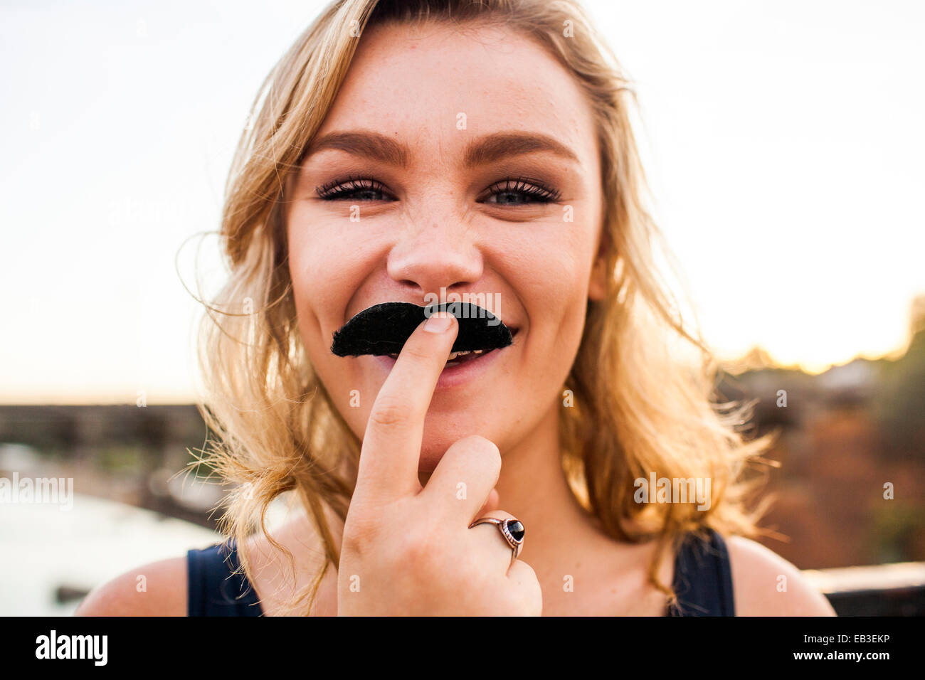 Caucasian teenage girl playing with fake mustache Stock Photo
