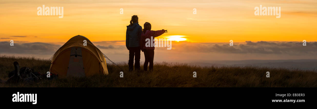 Silhouette of hikers overlooking remote landscape at sunset Stock Photo