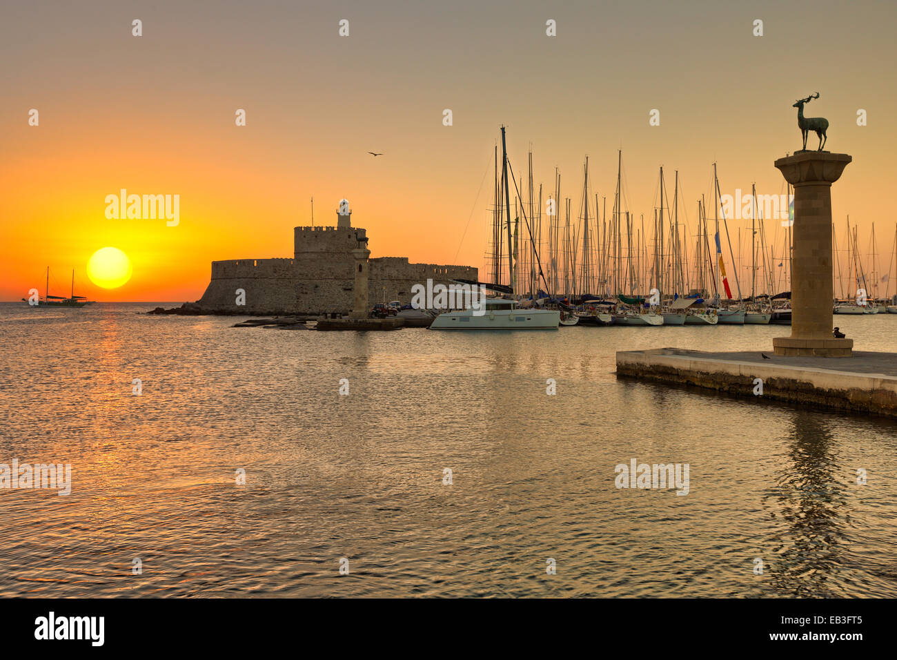 The sunrise at the entrance with the deers of the old port of Rhodes, Greece Stock Photo