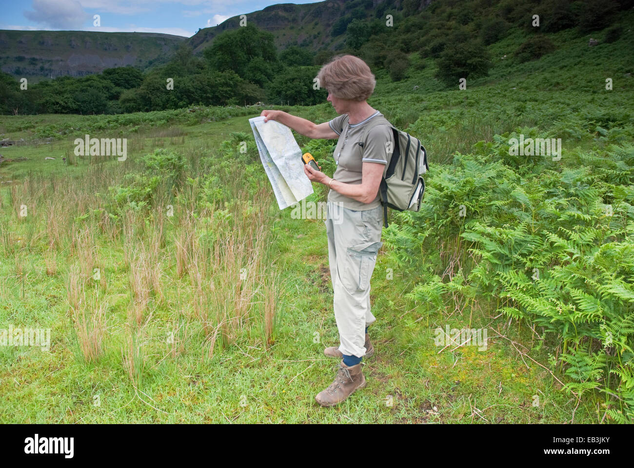 Female walker studying handheld outdoor gps device and Ordnance Survey
