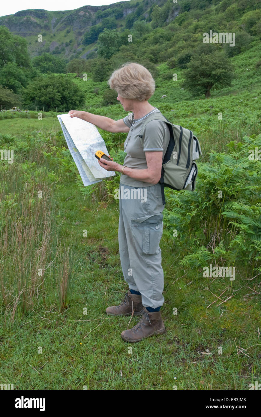 Female walker studying handheld outdoor gps device and Ordnance Survey