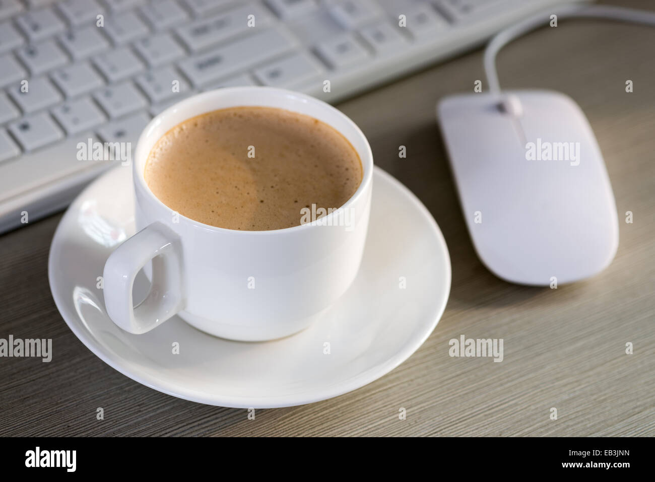 Close-up of the coffee, cellphone, pen and a cup of keyboard on the desktop Stock Photo