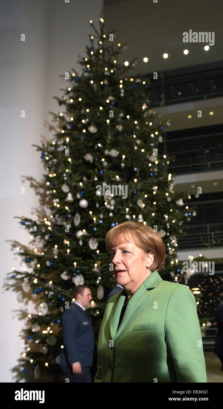 Berlin, Germany. 25th Nov, 2014. Chancellor Angela Merkel stands in front of a Christmas tree, a Caucasian fir from the Dobersdorf farm in the Ploen district, at the Federal Chancellery in Berlin, Germany, 25 November 2014. The Chancellery received three Christmas trees this evening. Photo: RAINER JENSEN/dpa/Alamy Live News Stock Photo