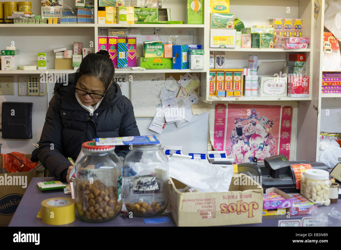 Female Chinese shopkeeper doing books in store in Chinatown at night-Victoria, British Columbia, Canada. Stock Photo