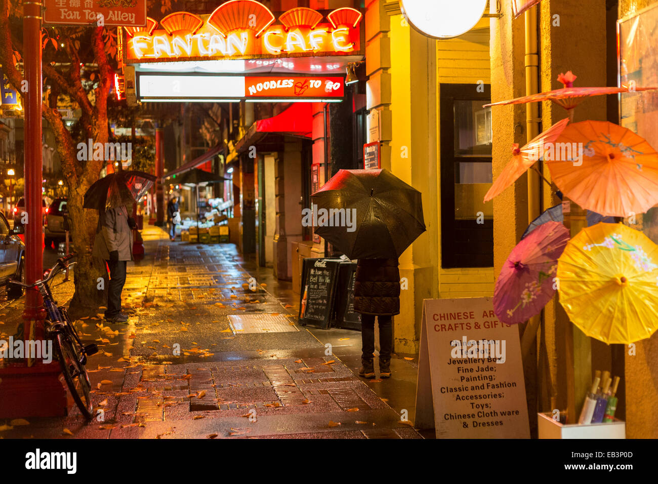 Chinese couple at Fan Tan alley entrance in Chinatown on rainy night-Victoria, British Columbia, Canada. Stock Photo