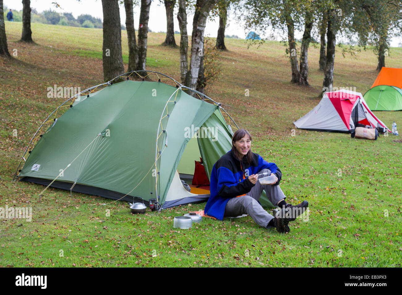 Camper outside tent eating, UK Stock Photo