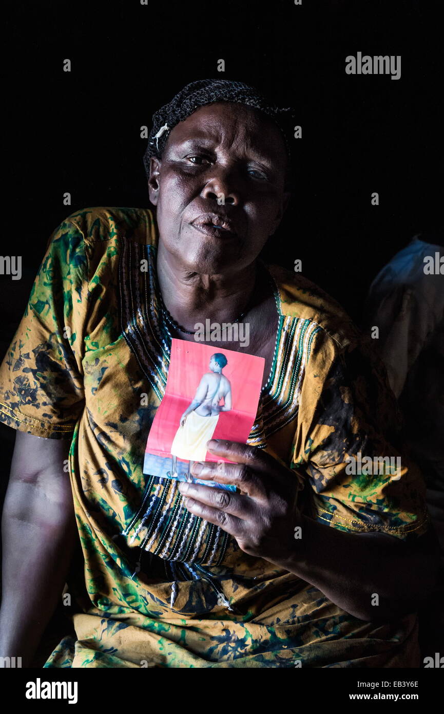 Gulu, Uganda. 21st Mar, 2014. PAULINE age 58, widow. Rebells killed her husband an village local councilor in 1998 while sleeping at their homestead. She got a land-mine blast traveling home from Gulu in 1996. Brother took care of her. She didn't receive any help or compensation. In 2010 she filled up the official registration form including the photo, which she is holding. From 1987-2006 thousands were brutally killed due the endless war between the LRA aka the Lord's Resistance Army of Joseph Kony and the official UPDF troops. © Peter Bauza/ZUMA Wire/ZUMAPRESS.com/Alamy Live News Stock Photo
