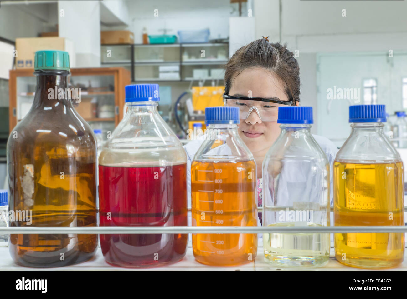 Close up of beautiful asian scientist looking at chemical bottle Stock Photo