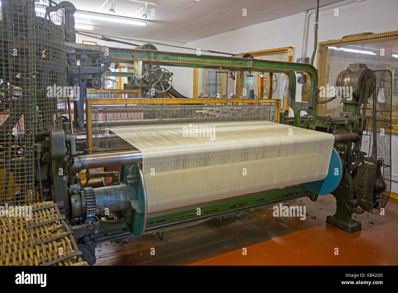 Large industrial loom with light coloured fabric being woven at Trefriw Woollen Mills, a popular tourist attraction in Wales Stock Photo
