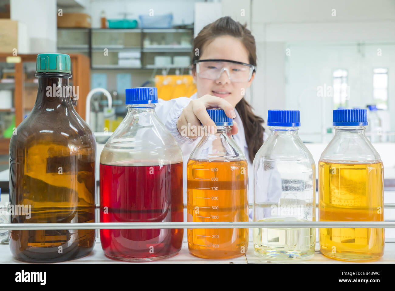 Asian scientist selecting bottle in shelf at laboratory (focus at bottle) Stock Photo