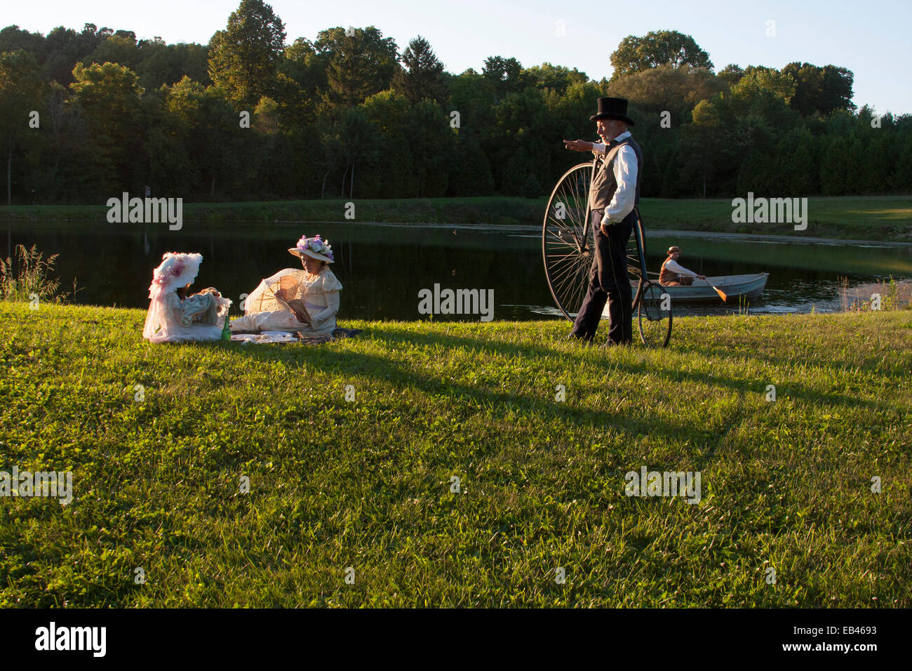 Victorian family with a bicycle next to a pond Stock Photo