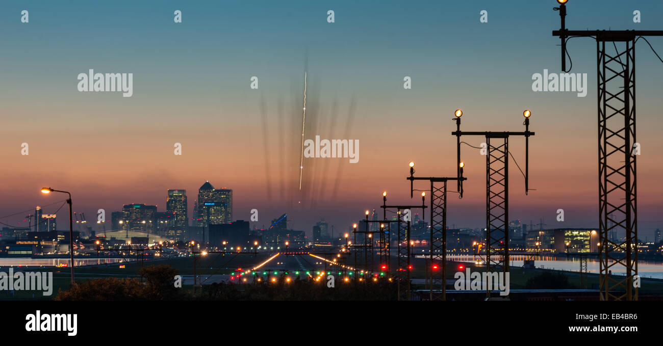 Plane landing at City Airport at sunset with Canary Wharf and Millennium Dome, now O2 arena backdrop Stock Photo